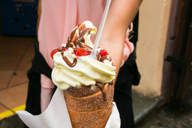Tourist holds in hand Trdlo or Trdelnik with ice-cream in the center of Prague Tourist holds in hand Trdlo or Trdelnik with ice-cream in the historic center of Prague trdelník stock pictures, royalty-free photos & images