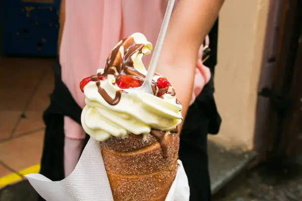 Photo of Tourist holds in hand Trdlo or Trdelnik with ice-cream in the center of Prague