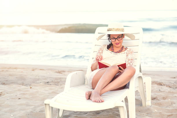 istock Young woman reading a book at beach 848603430