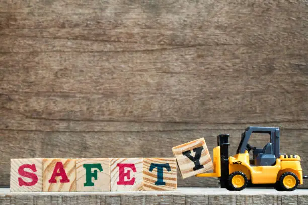 Toy plastic forklift hold block Y to compose and fulfill wording safety on wood background