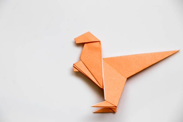 istock Origami orange paper fold as raptor dinosaur on white background 848610522