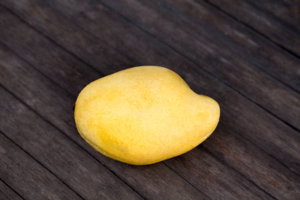 istock Pale yellow mango on wooden background. Tropical fruit mango on fruit market table. 848619388