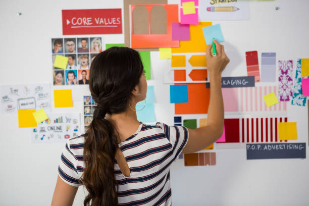 istock Rear view of woman writing on sticky note in office 848619936
