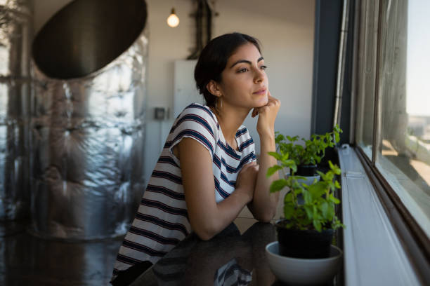 Thoughtful young woman looking through window at office