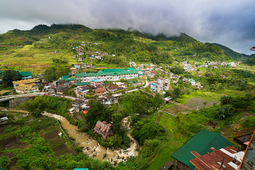 View over the village of Banaue and the mountains. Hanging bridge across the river.