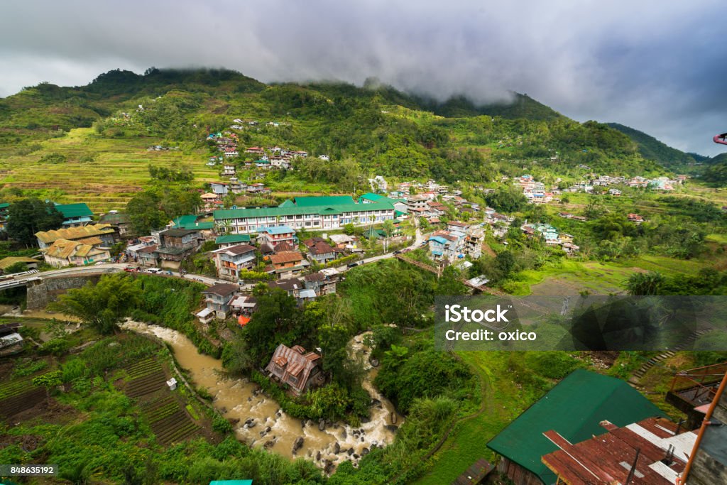 View over Banaue, Philippines View over the village of Banaue and the mountains. Hanging bridge across the river. Green Color Stock Photo