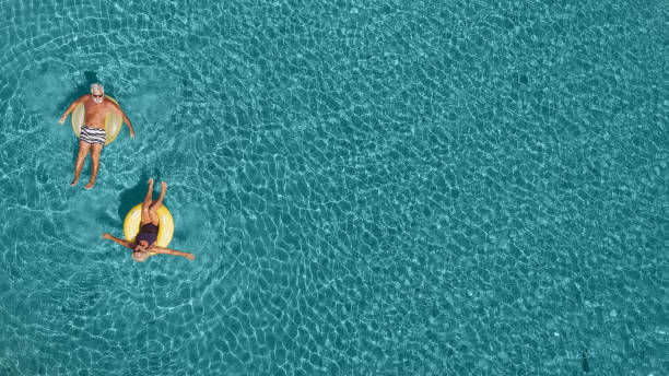 couple de personnes âgées s’amuser dans la mer - floating on water photos photos et images de collection