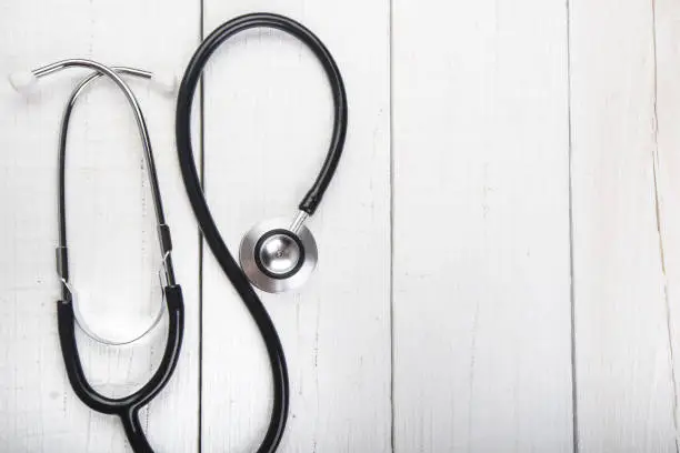 Photo of Stethoscope on a white wooden background. Copy space for a text. Pharmacy background on a white table. Medicine and healthy. Close up