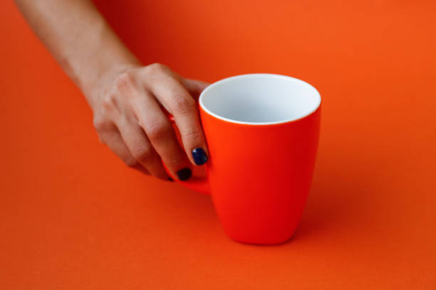 istock Hand holding orange cup on orange background 848662376