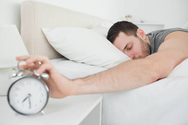 istock Sleeping handsome man being awakened by an alarm clock 848672060