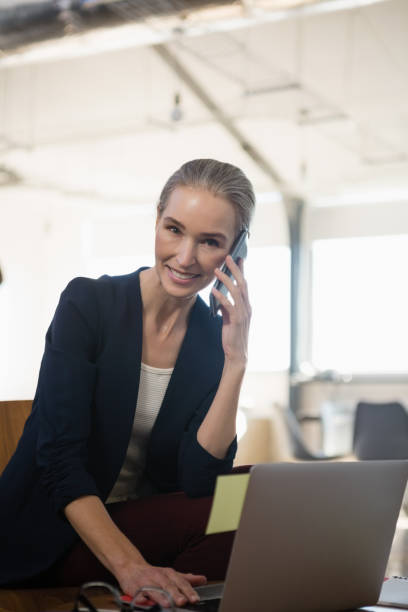istock Portrait of woman talking on phone while using laptop in office 848695808