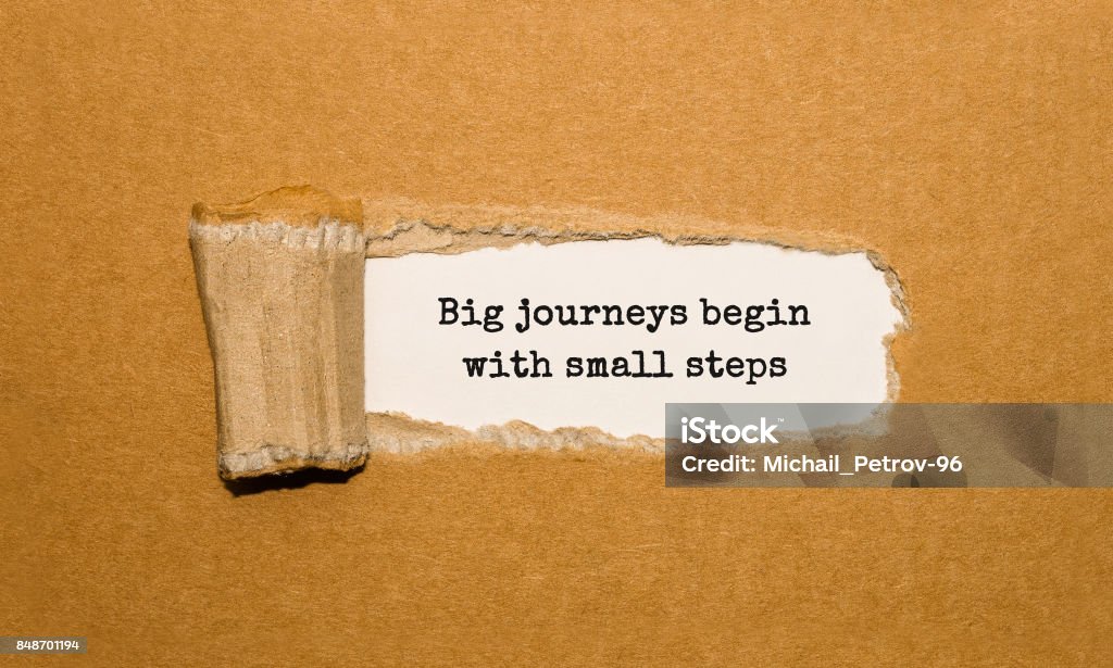The text Big journeys begin with small steps appearing behind torn brown paper Journey Stock Photo