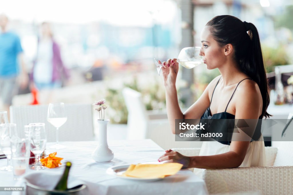 Woman tasting white wine in restaurant Woman tasting white wine in restaurant and lifting glass accordingly Adult Stock Photo