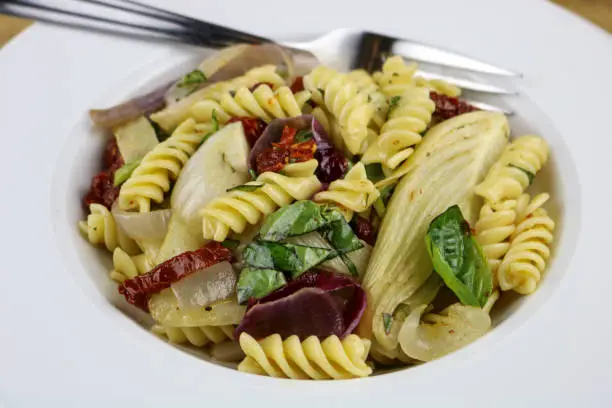 A bowl of Rotini pasta salad with fennel, artichoke and basil