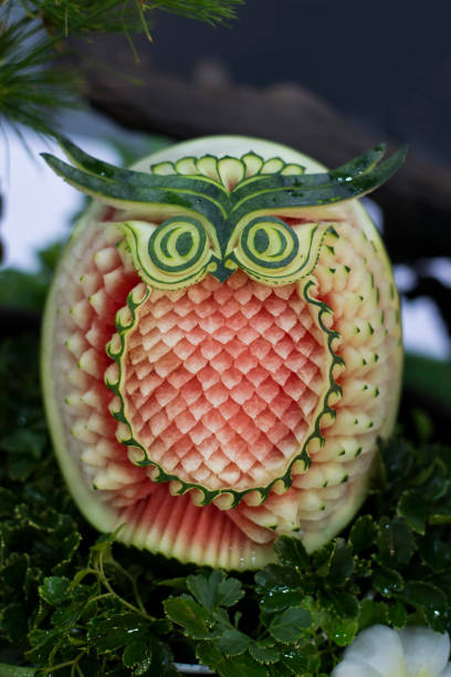 Thai fruit carving with watermelon into owl shape Thai fruit carving is a traditional Thai art that requires neatness, precision, meditation, and personal ability. Fruit carving persisted in Thailand as a respected art for centuries. carving fruit stock pictures, royalty-free photos & images