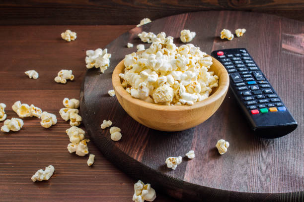 Salt popcorn on the wooden table Salt popcorn on the wooden table, selective focus remote control on table stock pictures, royalty-free photos & images