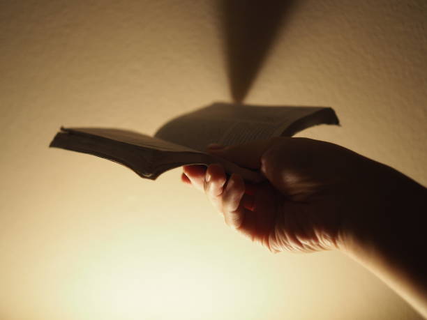 istock Hand holding small book, abstract corner shadow, yellow lamp light, grainy cement wall, dramatic 848741626