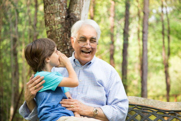 abuelo y nieto decir secretos al aire libre juntos. - whispering grandparent child grandfather fotografías e imágenes de stock