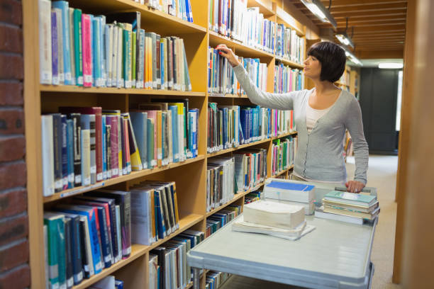 Librarian returning books Librarian returning books to shelf librarian stock pictures, royalty-free photos & images