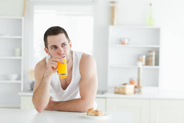 hombre joven beber jugo de naranja - instructor one person fruit drinking fotografías e imágenes de stock