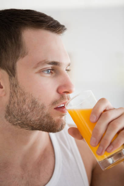 istock Close up of a young man drinking orange juice 848787432
