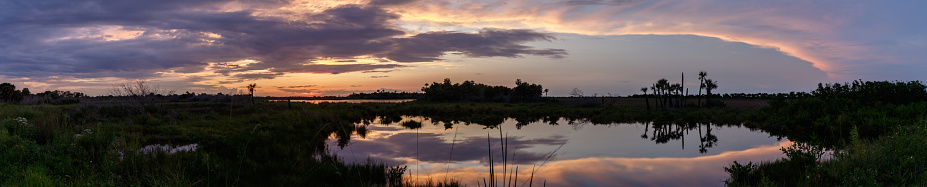 Sunset with clouds reflecting in a pond at Merritt Island National Wildlife Refuge, Florida, USA