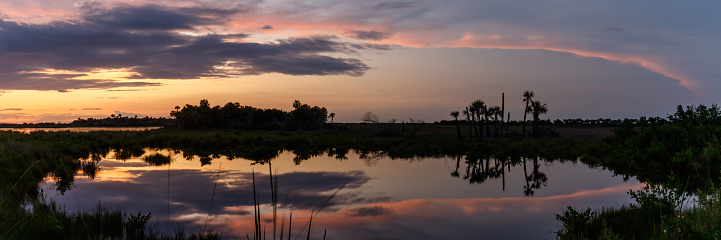 Sunset with clouds reflecting in a pond at Merritt Island National Wildlife Refuge, Florida, USA