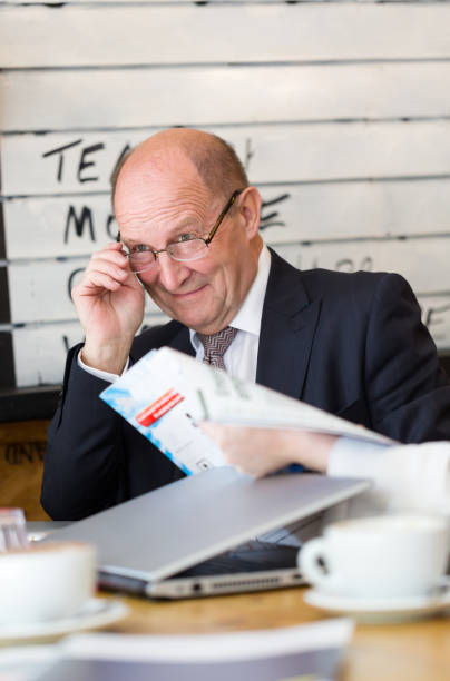 Senior manager, CEO, having conversation looks away holding glasses in hand