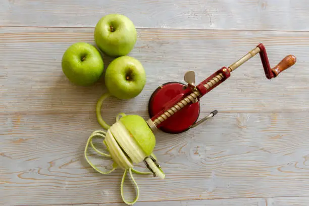 Granny Smith green apples with mechanical apple corer, peeler and slicer on rustic wooden boards.