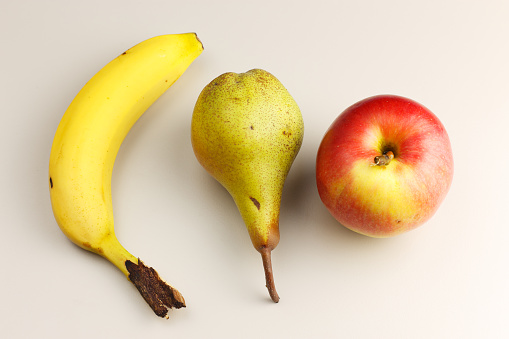 Yellow ripe banana, pear and apple studio shot photography.