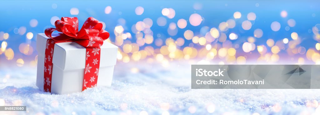 Regalo de Navidad en la nieve con luz desenfocada - Foto de stock de Regalo de navidad libre de derechos