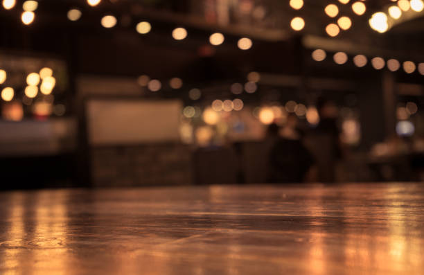 Wood table with blur light in night cafe,restaurant background Empty wood table top and blur of cafe restaurant in dark night background/selective focus .For montage product display busy restaurant tables stock pictures, royalty-free photos & images