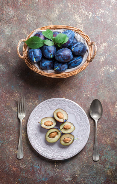 istock Plums in basket and halved plums on plate and tableware 848827250