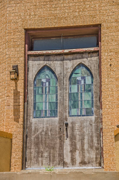 Old textured wooden doors with glass inserts on the side of a barn.