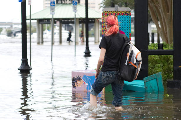 Jacksonville, FL, USA - September 11, 2017; A woman with long pink hair wades through flooded downtown Jacksonville, FL after Hurricane Irma took an unexpected turn and caused massive power outages and coastal flooding around the state.