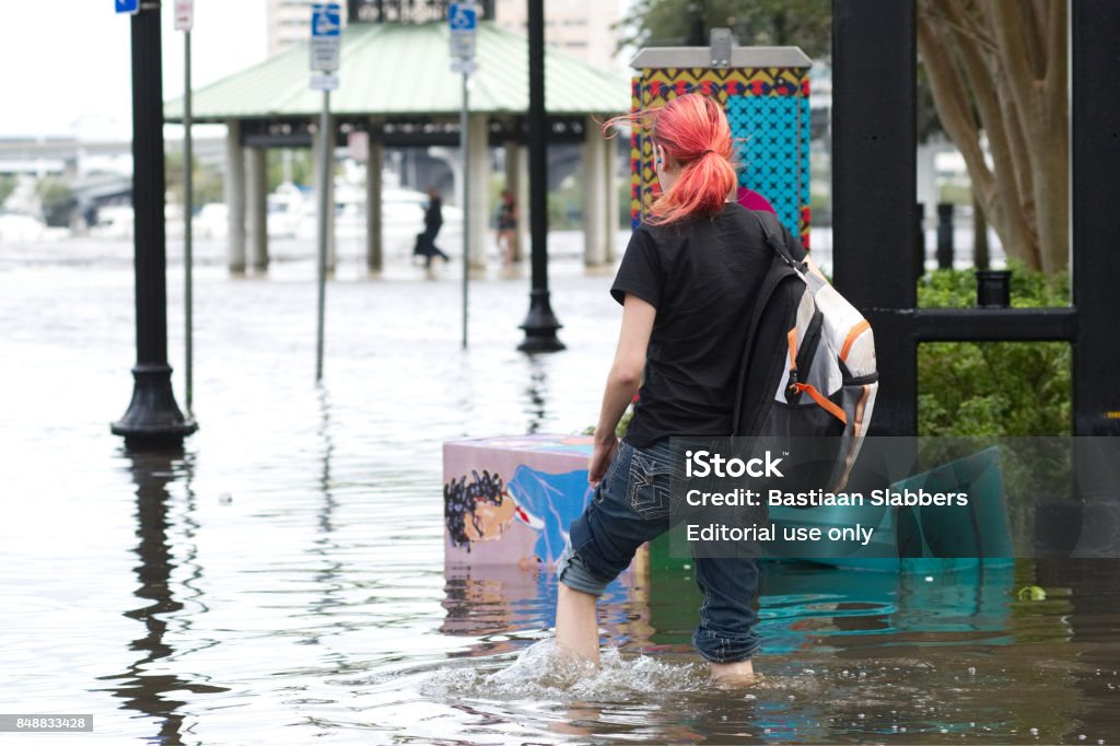 Hurricane Irma Strikes United States Jacksonville, FL, USA - September 11, 2017; A woman with long pink hair wades through flooded downtown Jacksonville, FL after Hurricane Irma took an unexpected turn and caused massive power outages and coastal flooding around the state. Hurricane - Storm Stock Photo