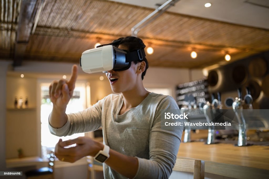 Hombre con casco de realidad virtual en restaurante - Foto de stock de Simulador de realidad virtual libre de derechos