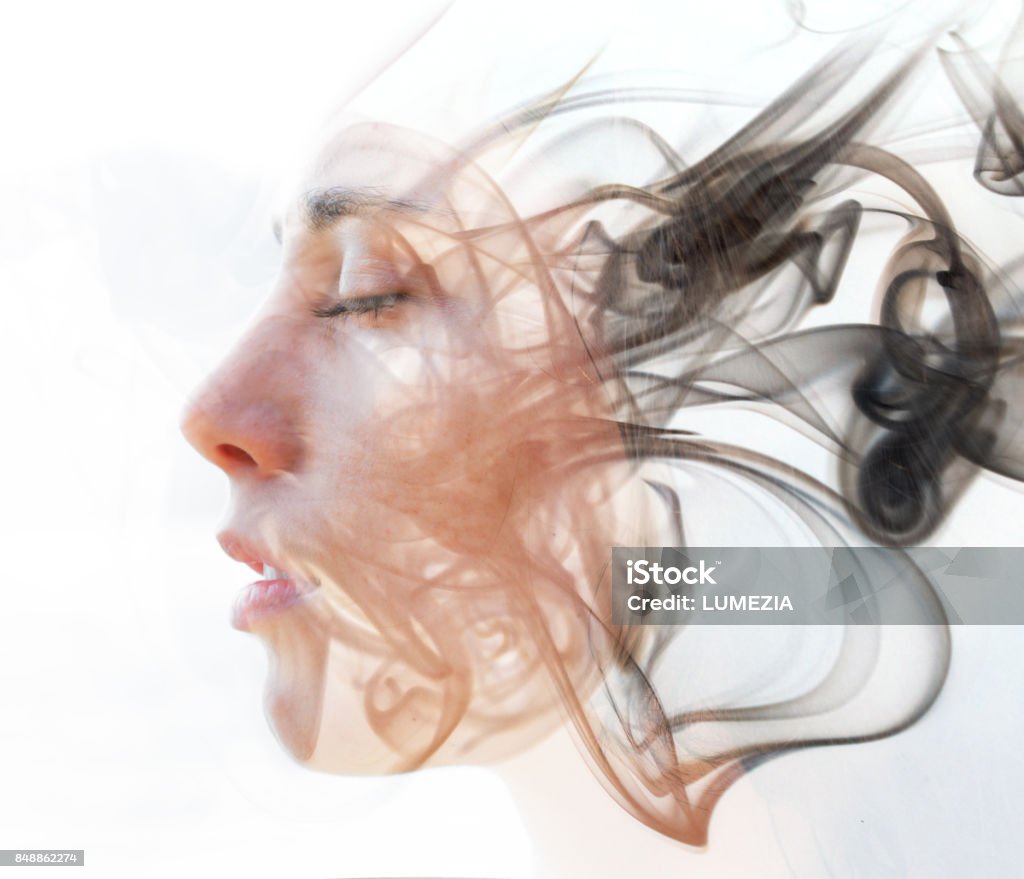 Double exposure portrait of a young fair-skinned woman and a smoky texture dissolving into her facial features D:"n"nWe see through the make up of her skin in a seemingly transparent veil of her being Hypnosis Stock Photo
