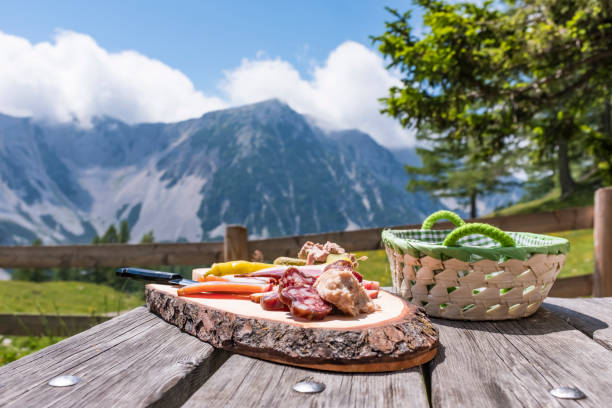 brettljause auf holztisch mit blick auf den gebirgszug karawanken - austria summer european alps mountain stock-fotos und bilder