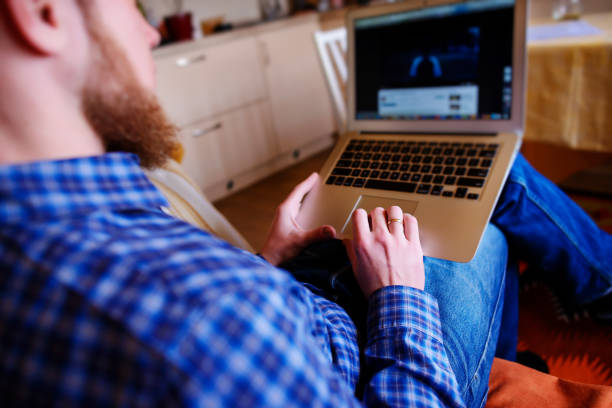 istock Young man working with computer on the beach. Handsome man working with laptop laying on the couch at the beach 848867186
