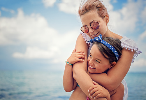 Mother is hugging her beloved daughter on the beach