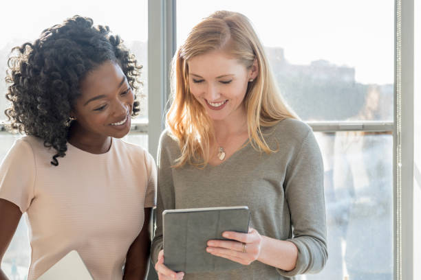 istock Two young businesswomen using tablet in modern office 848878282