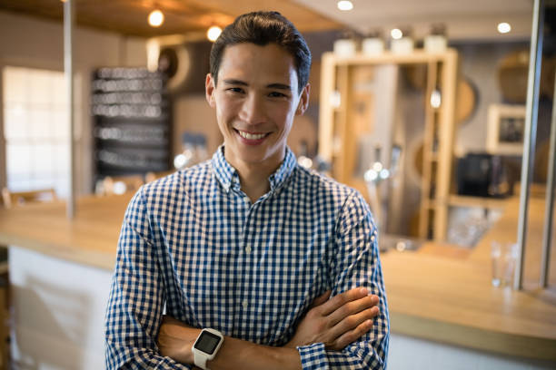 istock Smiling man standing with arms crossed at counter in restaurant 848884076