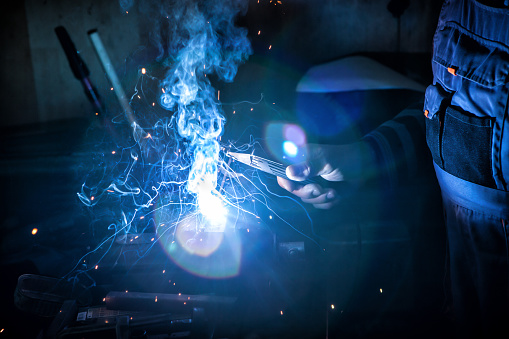 Senior caucasian mechanic in his factory welding metal part of bicycle