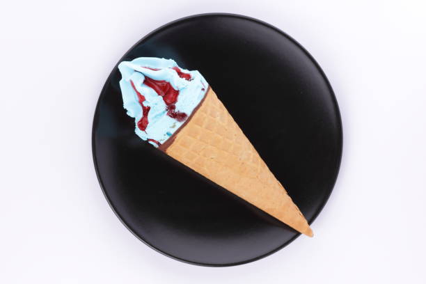 istock Ice cream in a waffle cup with a multicolored filling and red jam on a black plate with a wooden spoon for the designer 848902578