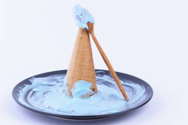Ice cream in a waffle cup with a multicolored filling and red jam on a black plate with a wooden spoon for the designer