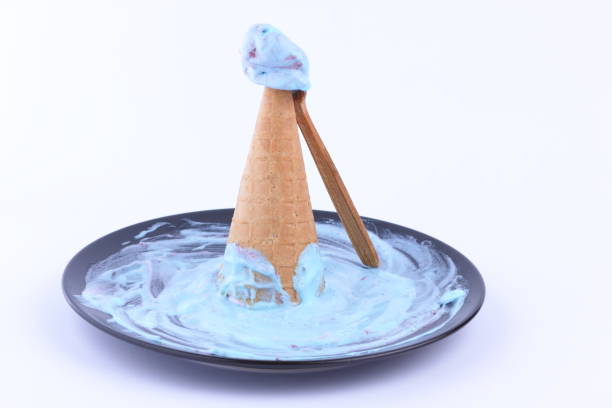 Ice cream in a waffle cup with a multicolored filling and red jam on a black plate with a wooden spoon for the designer