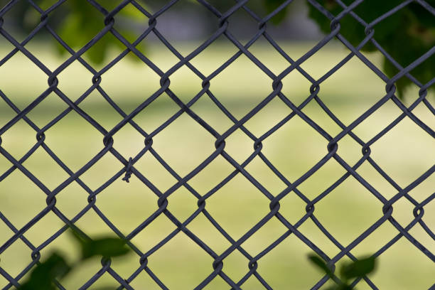 istock Chain linked fence with green field behind 848910412