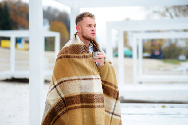 un jeune homme de boire un café avec coupe debout sur la beac automne - beach on child the photos et images de collection