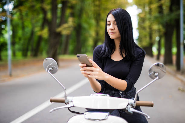 istock Smiling young woman looking at her mobile phone, sitting on scooter 848946400